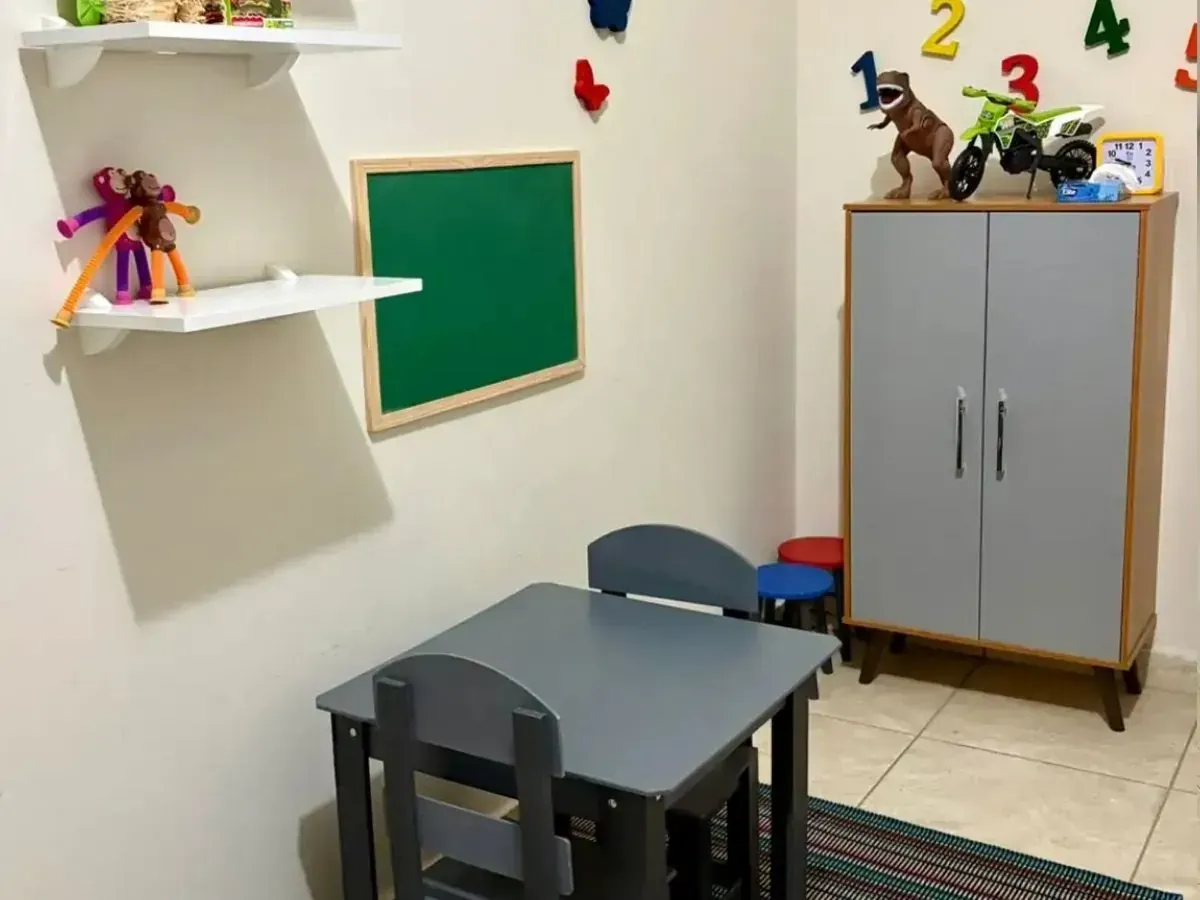 Sala lúdica infantil com brinquedos, mesa e lousa