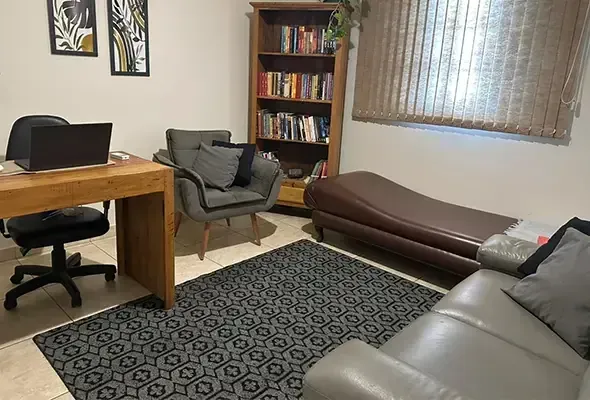 Sala de atendimento com divã, poltronas e mesa