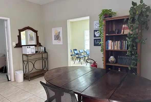 Hall de entrada da clínica decorado com mesa redonda, estante de livros e plantas, criando um ambiente acolhedor para orientação em psicanálise em Campinas.