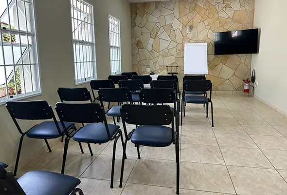 Sala de palestras organizada com cadeiras, tela e flip chart na Clínica de Psicanálise em Campinas, pronta para realização de cursos e eventos.