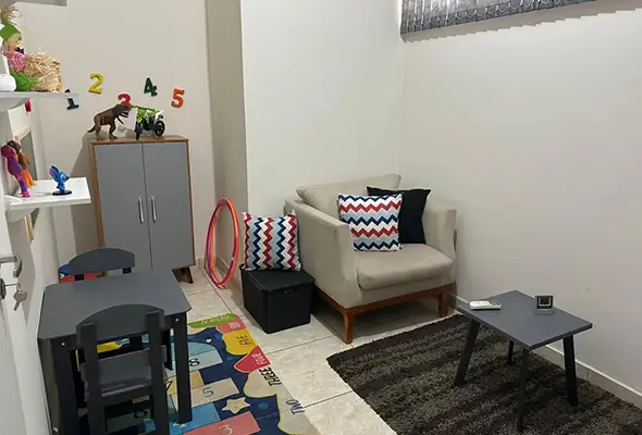 Sala de terapia infantil montada com mobiliário adequado, tapete de atividades e brinquedos, disponível para locação por psicólogos infantis em Campinas.