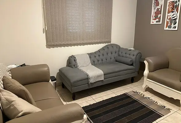 Consultório aconchegante equipado com divã moderno, poltronas confortáveis e tapete, disponível para locação para terapeutas e psicólogos.