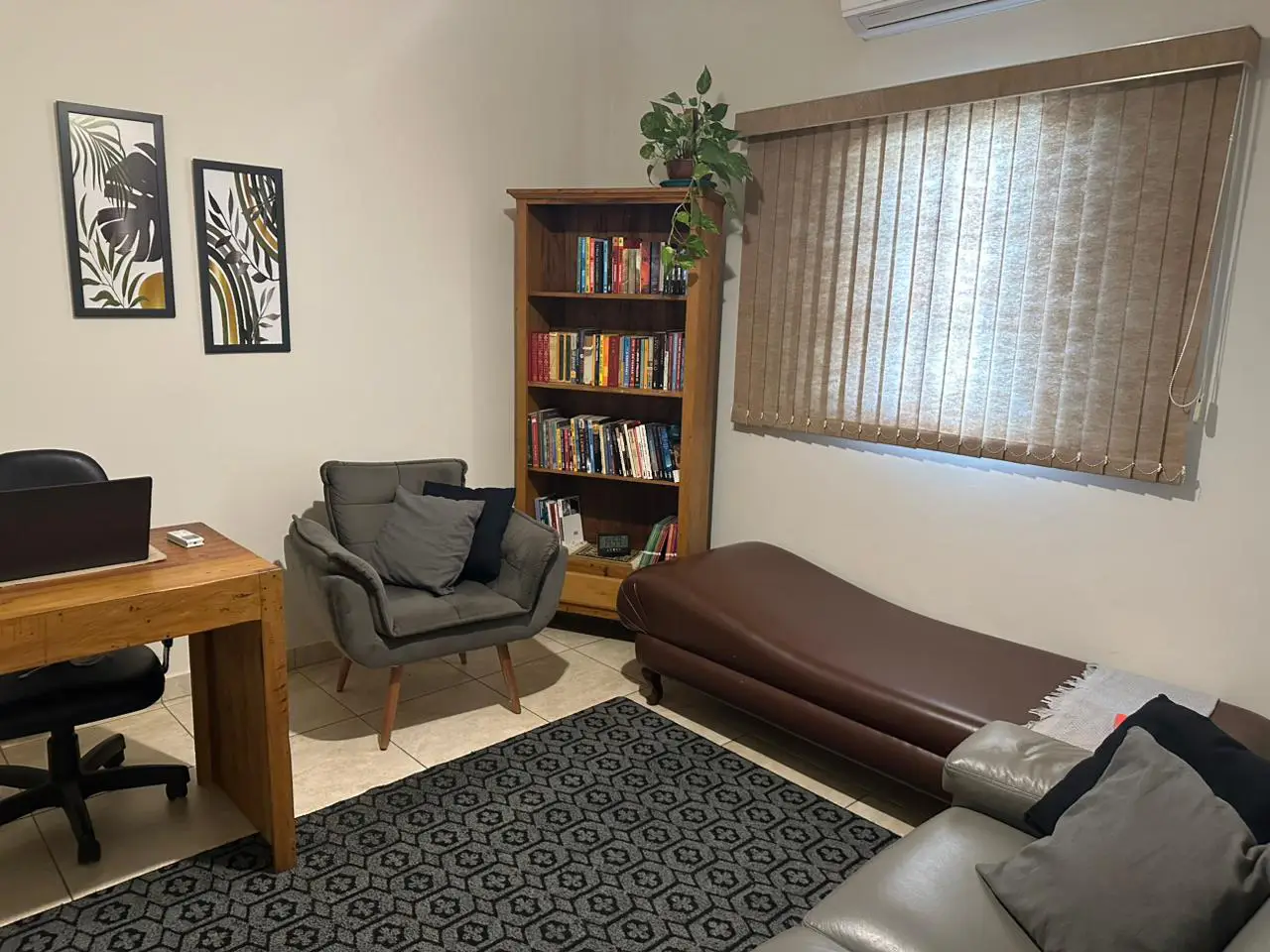 Sala de atendimento completa com divã, poltrona e mesa, disponível para locação por psicólogos no bairro Taquaral, em Campinas.