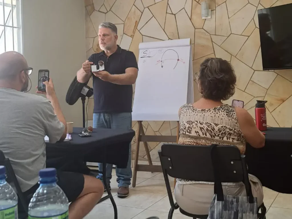 Supervisor clínico em pé demonstrando conceitos teóricos com apoio de flip chart e objeto visual para alunos durante supervisão de casos em psicanálise no Nuamce Campinas.